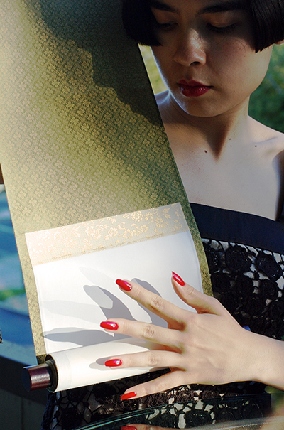 Drue Kataoka gazing down at an unrolled Japanese scroll mounted in green silk brocade