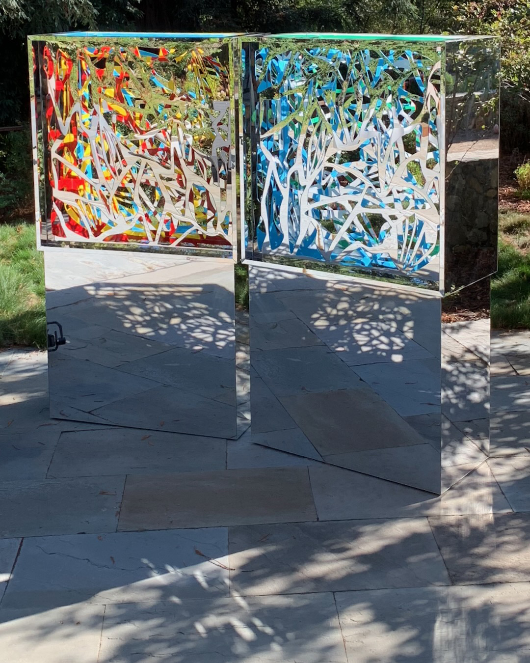 Two Ambrosias on mirrored pedestals catching the light in a garden