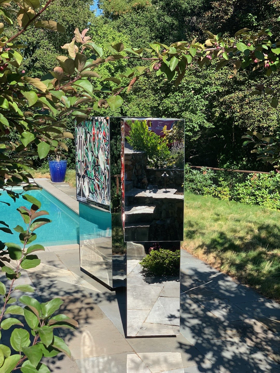 An Ambrosia beside a garden swimming pool, framed by crabapple branches