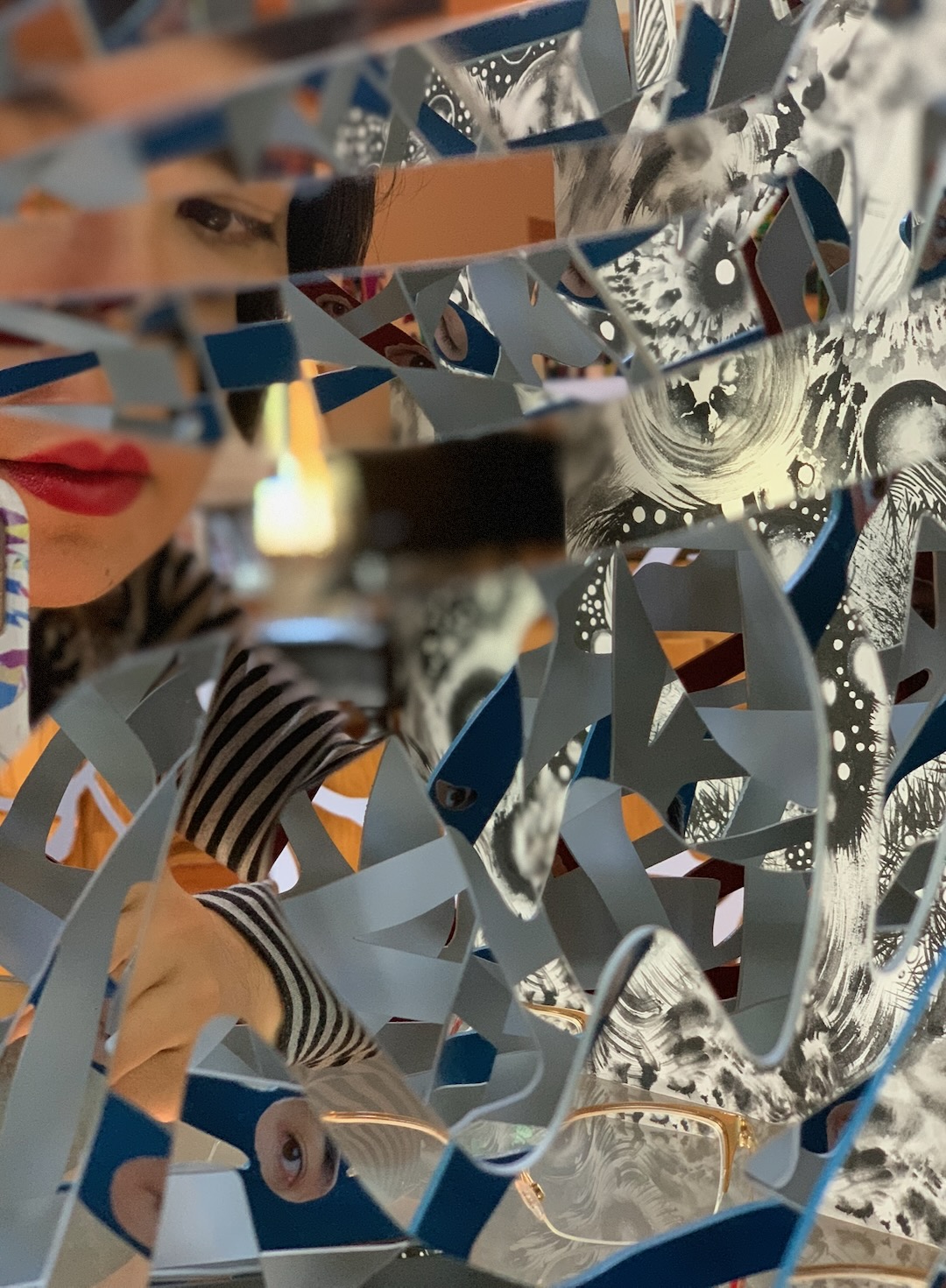 A woman's face glimpsed through blue-gray Ambrosia panels painted with black-and-white imagery