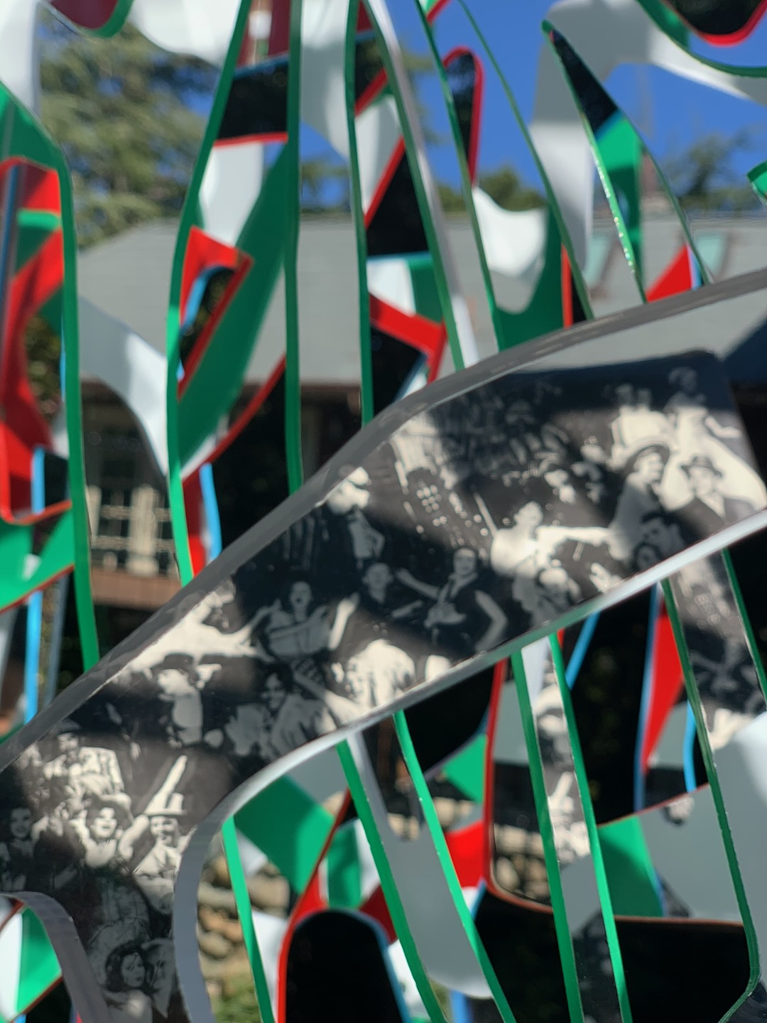 Detail of green, red and white Ambrosia panels with a band of black-and-white archival imagery against blue sky