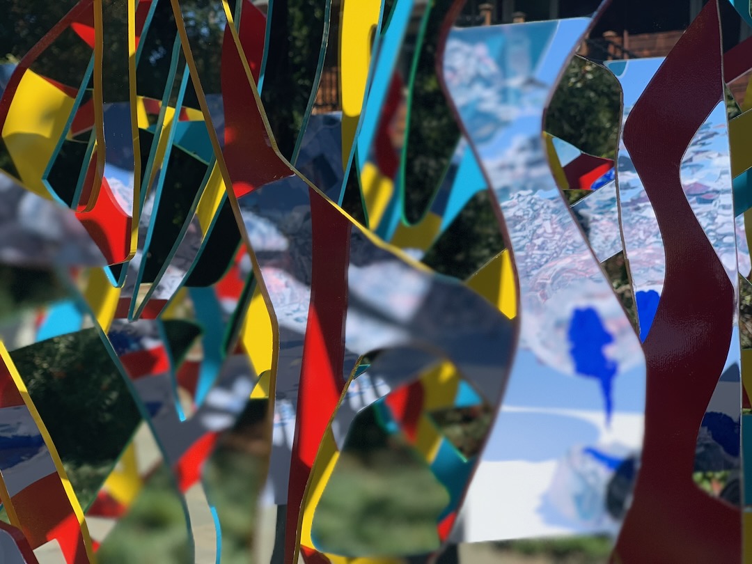 Detail of red, yellow and cyan Ambrosia ribbons with painterly blue imagery on the mirrored surface