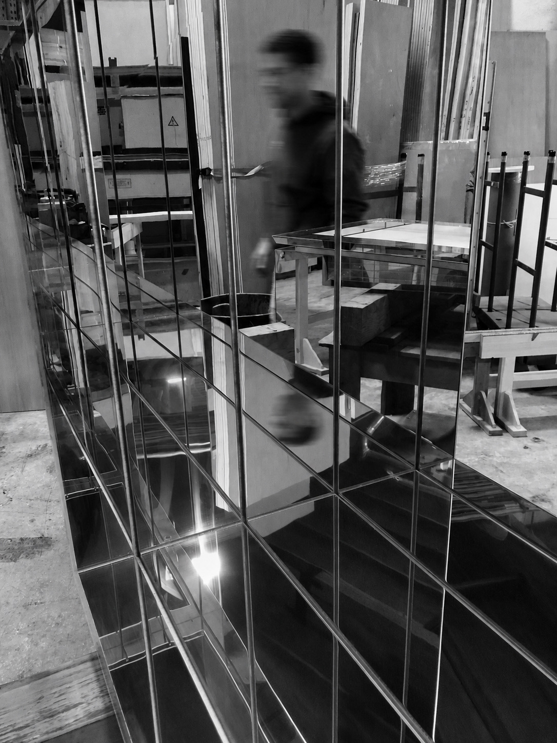 An Ambrosia's modular mirror panels reflecting the studio as a team member passes behind