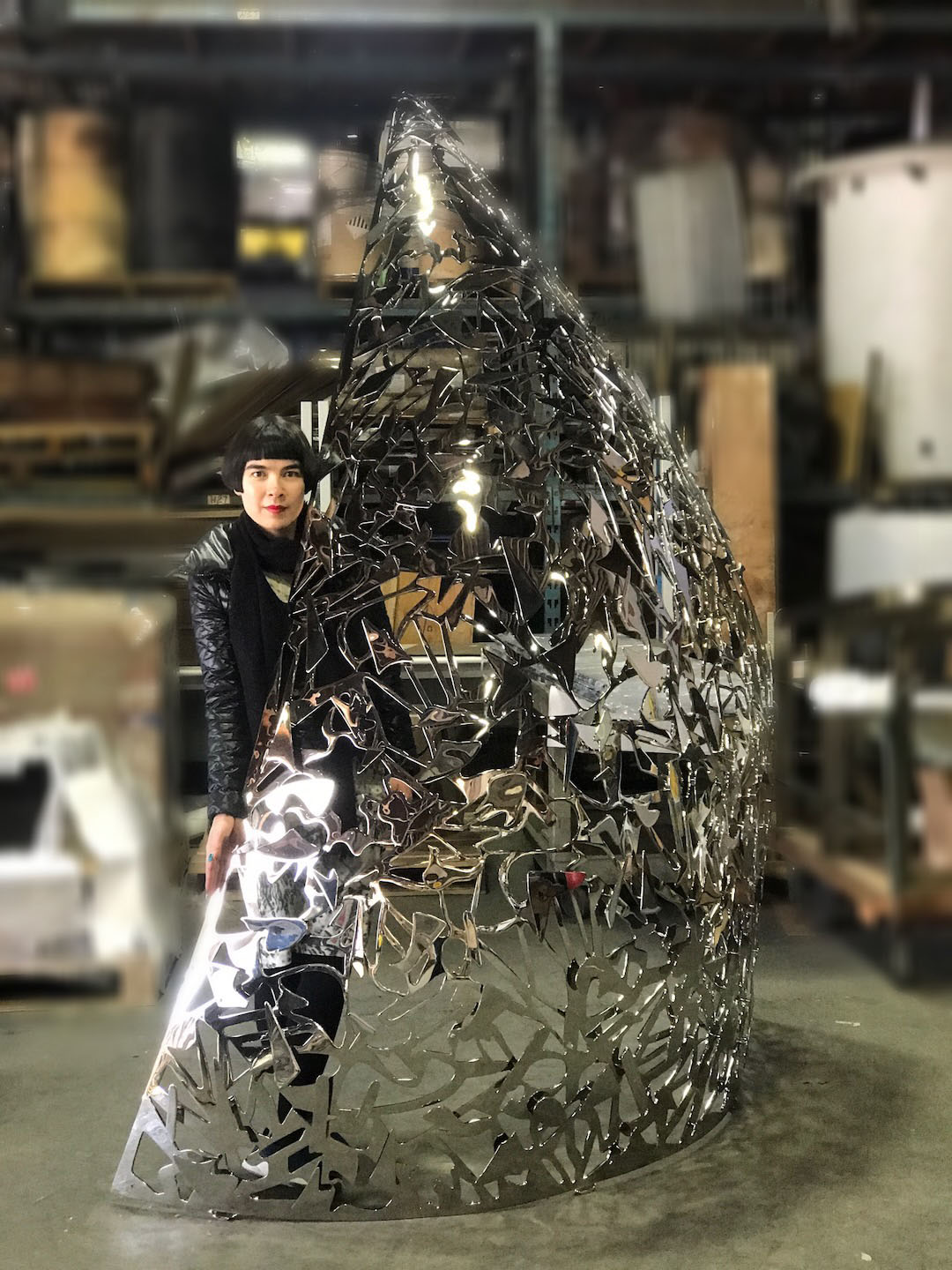 Drue Kataoka beside a Celestial Lace sculpture in mirror-polished steel, in the workshop
