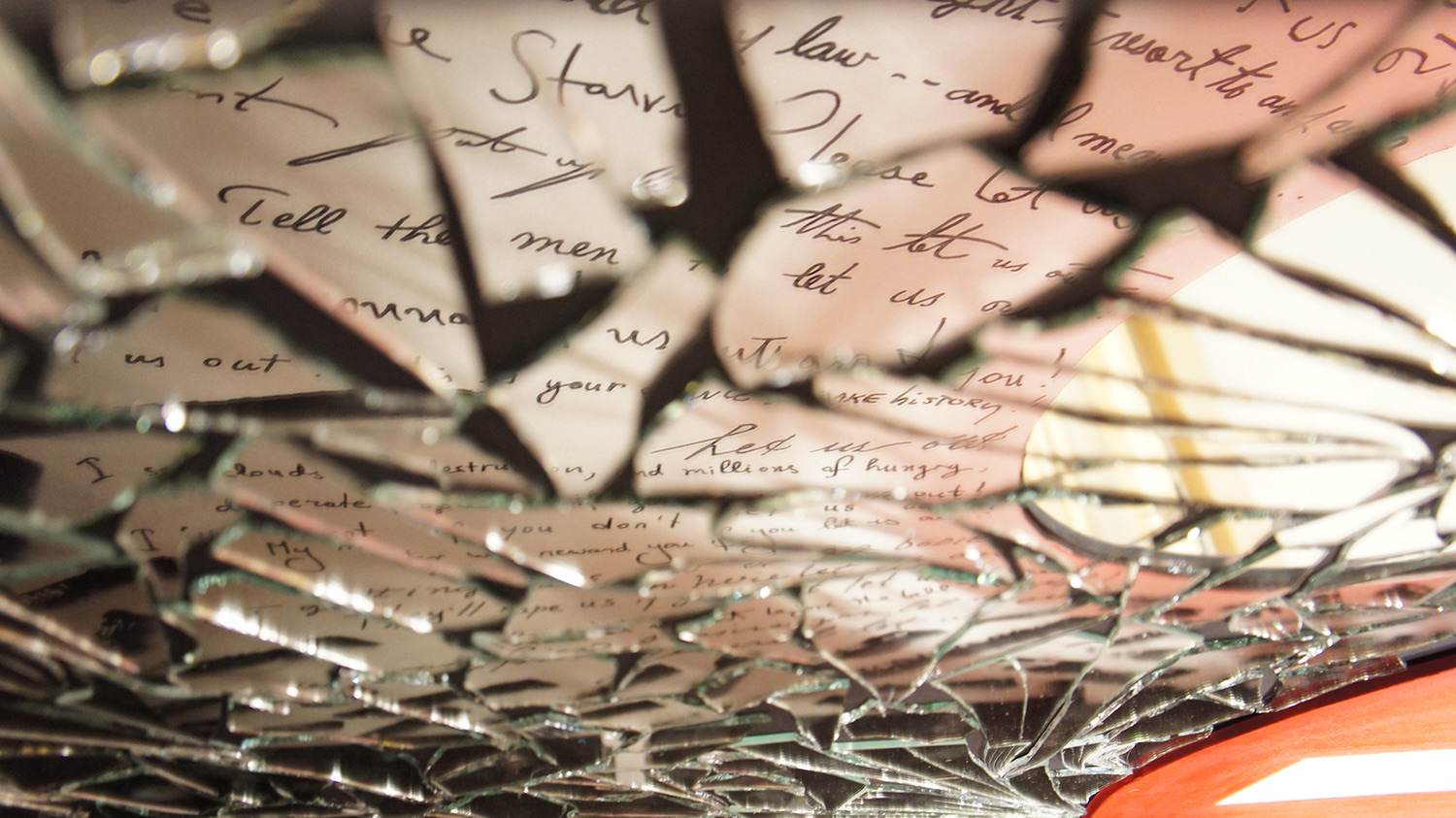 The voices — handwritten 'let us out' statements painted in reverse around the No Entry sign, legible in the mirror fragments