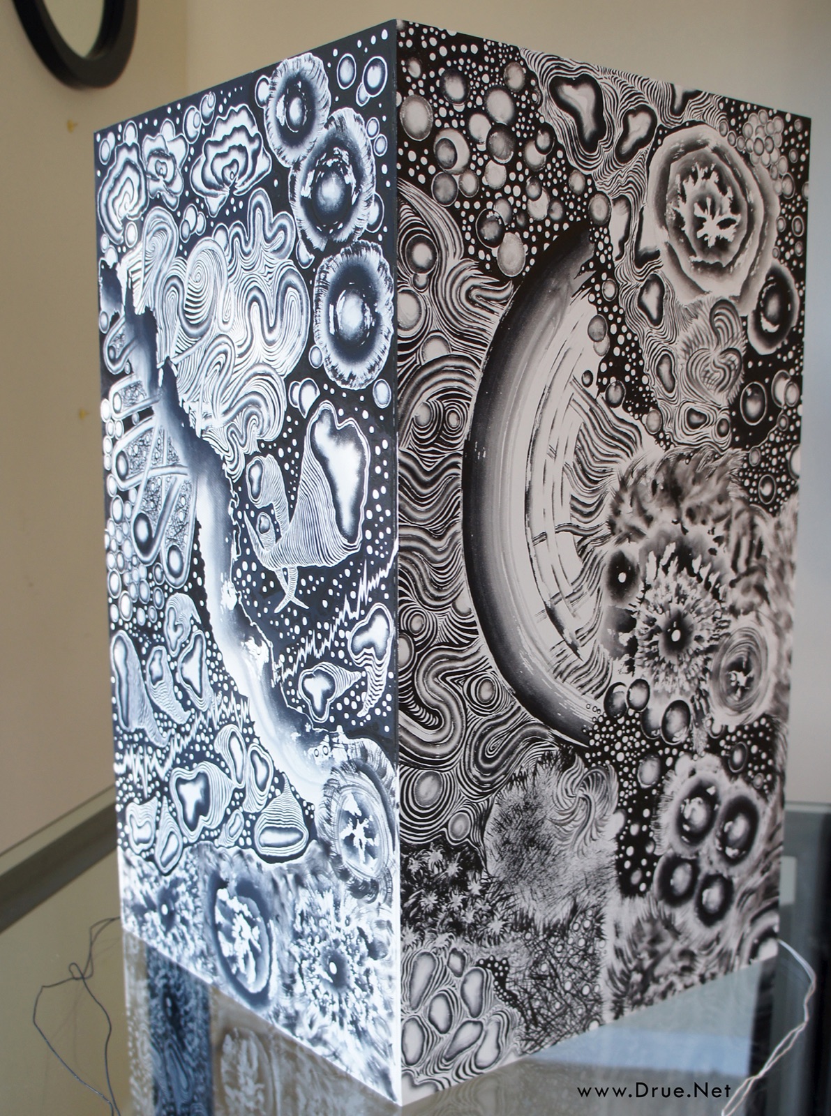 The Tree of Pascal box covered in sumi ink paintings — whales, brainwaves, and cellular forms — standing on a mirrored table