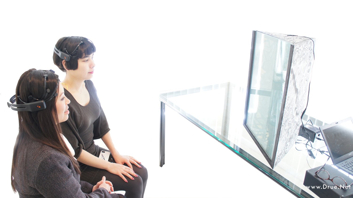 Two participants wearing EEG headsets control the transparency of the glass box with their brainwaves